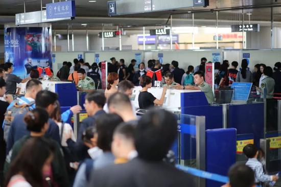 ▲资料图:青岛机场边检站民警为出境游旅客办理通关手续。