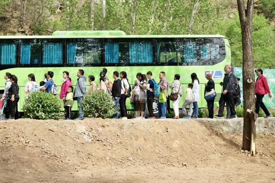 乘客从古北口站出站后换乘免费接驳公交前往古北水镇景区。摄影/新京报记者 郑新洽