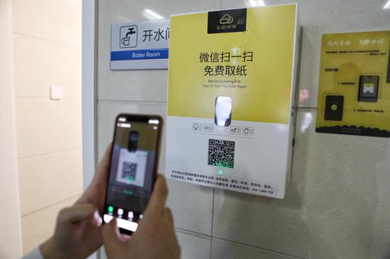 今年4月16日,北京安贞医院门诊楼厕所外,一名女士在用微信扫码取纸。摄影/新京报记者 王嘉宁