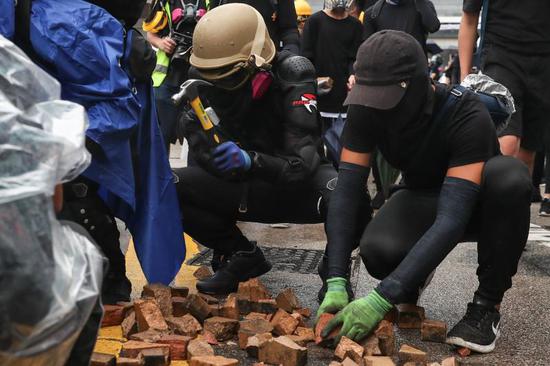 蒙面暴徒拆毁路上砖块，用以作为攻击警方的武器。