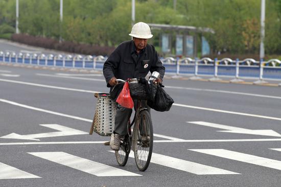 吴锦泉骑车外出磨刀(新华社)
