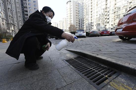 物業服務管理中心的工作人員在對下水道口進行消毒。