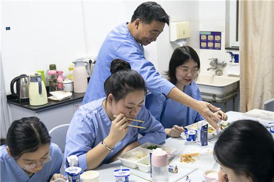 1月24日,武汉大学中南医院重症医学科的主任彭志勇(左三)给同事马晶分发糖果,作为年夜饭的“加餐”。新华社记者 熊琦 摄
