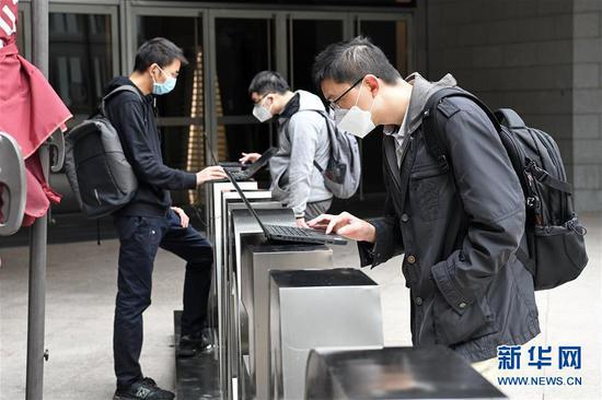 在深圳平安金融中心,企业员工在楼下使用笔记本电脑连接公司内网下载安装远程办公软件,以便实现居家“云办公”(2月10日摄)。新华社记者 梁旭 摄