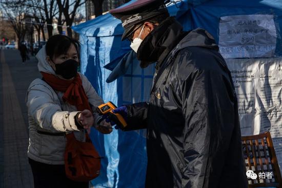 △ 3月4日，北京望京，华鼎世家B门，保安正在为居民测量体温。