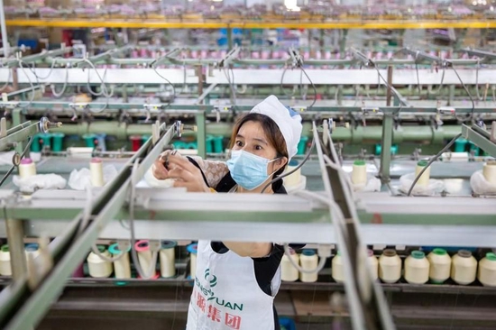  6月15日，江苏省海安市高新区一丝绸纺织企业车间内，工人在生产线上忙碌。新华社发（翟慧勇 摄）