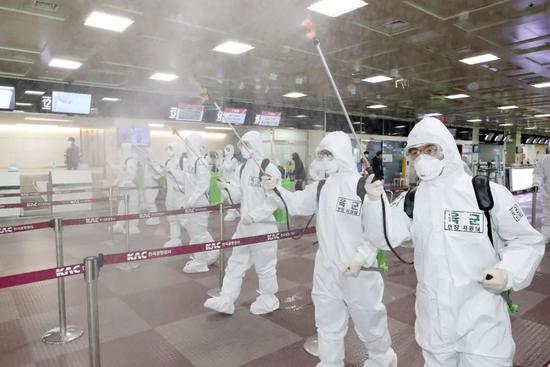 3月6日，在韩国大邱机场，工作人员喷洒消毒剂。新华社/法新