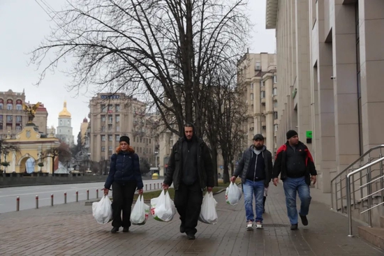 2月24日，在乌克兰基辅，当地居民拎着采购的物资走在街道上。新华社记者 李东旭 摄