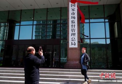 资料图：4月10日，新组建的国家市场监督管理总局在北京正式挂牌。图为民众与新牌合影。 中新社记者 贾天勇 摄