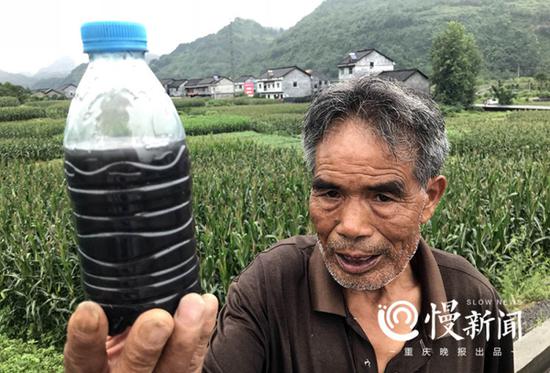 村民黎年武拿出一个装满黑色污水的瓶子。他称，这就是6月27日当天他从堰渠中接取的污水样品。