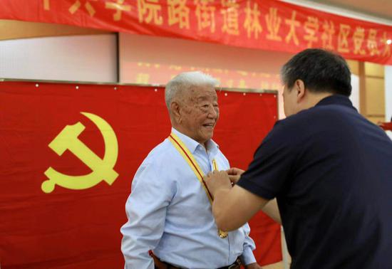 街道党工委领导为老人佩戴党徽。摄影/新京报记者 浦峰