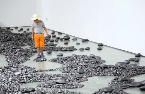  艺术家孟柏伸的作品《河》的展览现场布满了用铅笔涂抹过的石子，观众可以任意穿梭，感受其中的魅力。