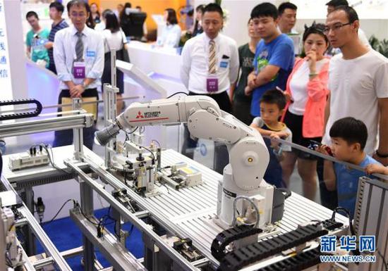 8月15日，观众在机器人大会上参观一款工业机器人。张晨霖 摄