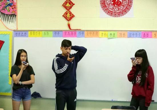 几位学习汉语的佩顿中学学生在汉语教学课上练习汉语表达并用手机录下。 新华社记者 汪平 摄