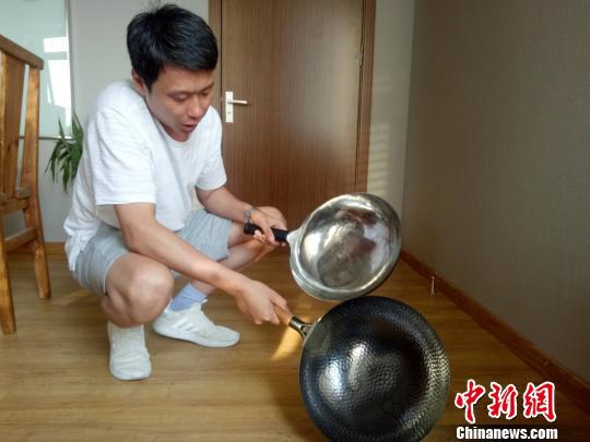 图为章丘铁锅“同盛永”“臻三环”品牌负责人刘紫木向记者介绍如何区别真假铁锅。　赵晓 摄