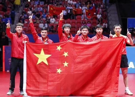 图为中国队队员和教练刘国正(左二)夺冠后手持国旗庆祝。