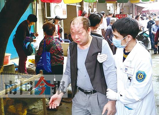 一名被烧伤的老人正被急救医生扶着走向救护车。他的头发被烧焦，头部被烧伤。记者张存立 摄