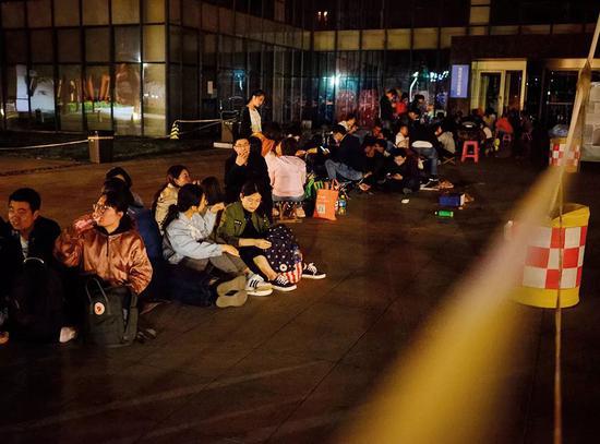（2018年5月23日晚，天津市河西区行政许可服务中心，自发集中门外排队等待落户的人们。图/视觉中国）