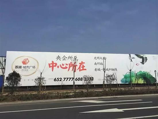 ▲2014年底，苏润城市广场竖立在霍邱县当地的大幅广告牌明确提及央企字眼。图/新京报