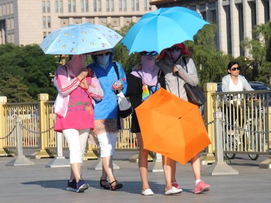 △日前，游客在北京天安门及长安街游览，采取打伞、戴遮阳帽、墨镜等措施防晒。
