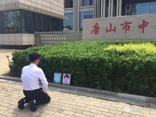 ▲获无罪后,廖海军在法院门前朝父母遗像磕头告慰。新京报记者 赵凯迪 摄