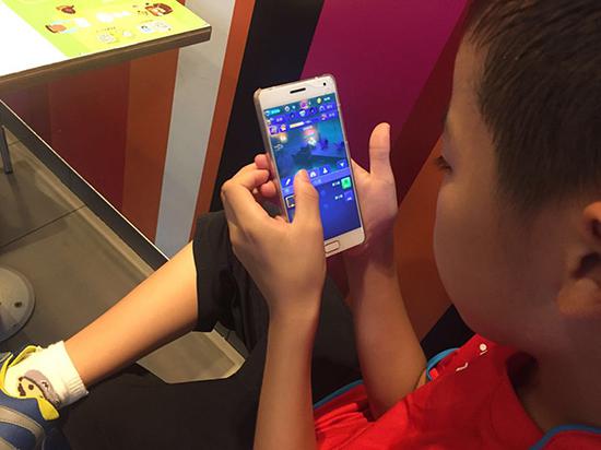 梁昊拿着爸爸的手机，游戏玩得入了迷。