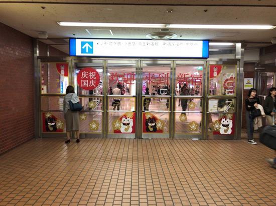 台风来临之际正值十一黄金周，日本新宿的地铁站出口打出了“庆祝国庆”的中文标语