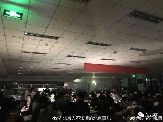 食堂断电,学生借手机亮光继续吃饭/图片来源见水印