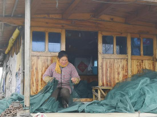 围网拆除后，渔民段元兵的妻子在家制作地笼网，补贴家用。新京报记者陈景收 摄