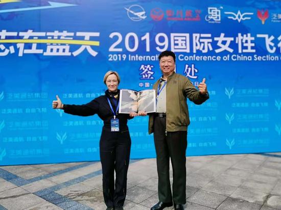 中國航空攝影家牟健爲和丹麥女航空畫家、飛行員、攝影家Simone Aaberg Kaern 女士,互拜老師。牟健爲贈送其攝著的《航空攝影教程》。