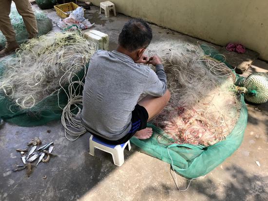 一位渔民捕鱼回来后收拾网具。