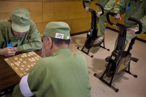 娱乐室里,玩日本将棋的老年囚犯,一旁还有两名囚犯使用动感单车。