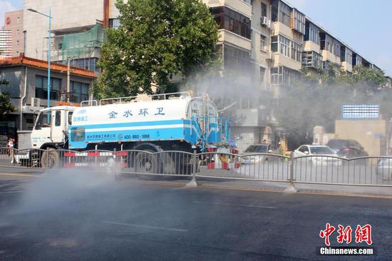 郑州花园路,一辆高压冲洗车辆对道路进行洒水降尘处理,水花四溅。 马义恒 摄