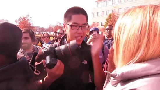 在密苏里大学报道师生扎营抗议校方种族歧视行动时，华裔记者戴睿光(中)被粗暴包围驱赶。(图：取自youtube)