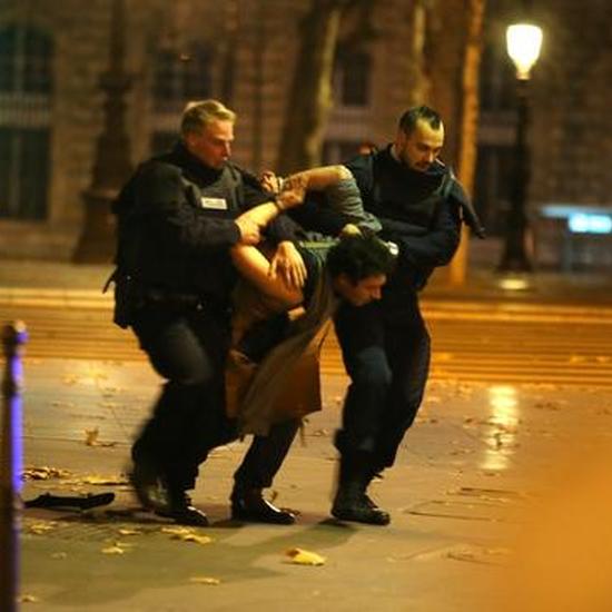当地时间2015年11月13日晚，巴黎警察持枪在遭劫持的巴塔克兰剧院外逮捕一名嫌疑人。