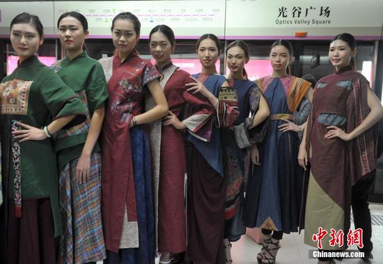  12月4日，武汉地铁2号线一列看似普通的列车车厢瞬间变T台，22名大学生模特身着旗袍和晚礼服上演了一场地铁时装秀，吸引不少乘客观看。中新社记者 张畅 摄
