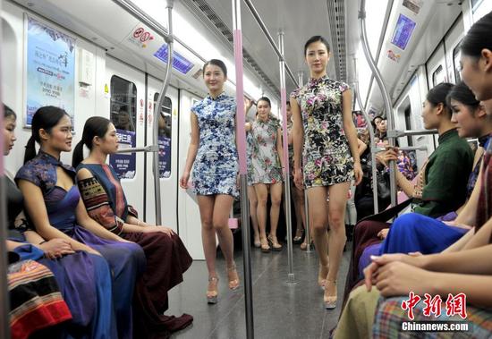 12月4日，武汉地铁2号线一列看似普通的列车车厢瞬间变T台，22名大学生模特身着旗袍和晚礼服上演了一场地铁时装秀，吸引不少乘客观看。中新社记者 张畅 摄