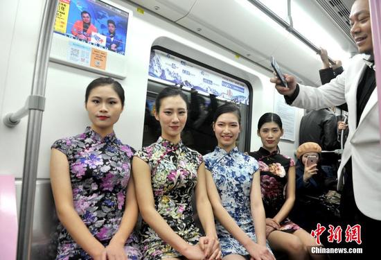 12月4日，武汉地铁2号线一列看似普通的列车车厢瞬间变T台，22名大学生模特身着旗袍和晚礼服上演了一场地铁时装秀，吸引不少乘客观看。中新社记者 张畅 摄