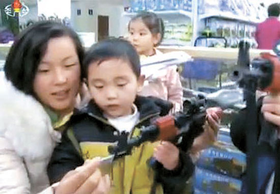 图为正在平壤市苍光商店一层玩具卖场挑选玩具枪的朝鲜儿童。【照片：朝鲜中央电视台截图】