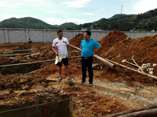 2015年6月18日，湖南新宁县教育局局长周光辉（右）在高桥镇中心小学建筑工地检查。新宁教育网图