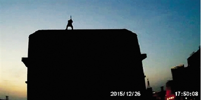 视频截图显示，轻生男子在楼顶挥动钢管 