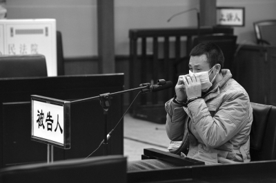 2015年11月25日，包建国戴着口罩出庭受审。京华时报记者 赵思衡 摄
