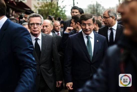 1月13日，在土耳其伊斯坦布尔，土耳其总理达武特奥卢（右）与德国内政部长德迈齐埃（左）前往苏丹艾哈迈德广场悼念遇难者。（新华社/法新）