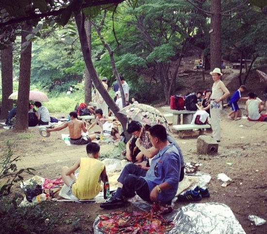 许多朝鲜家庭在首都牡丹峰公园中冒雨野餐。