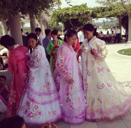 在金日成和金正日陵墓外面，当地女子穿着传统朝鲜礼服躲在阴凉处。