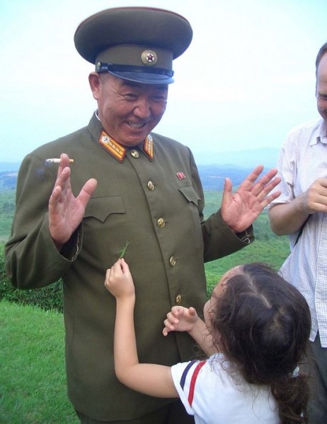 一名朝鲜军官正与一名小女孩玩耍，这与西方媒体中面容严肃的朝鲜军人的形象完全不同。