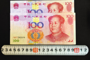 “加长版”百元钞票对比，明显比其它钞票长一点，防伪线和字体的位置也不同。　本报记者　杨伟广　摄