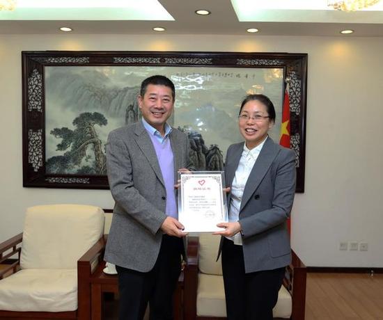 团中央书记处书记、中国青年志愿者协会会长汪鸿雁（右）向飞鹤乳业董事长冷友斌（左）授予捐赠证书