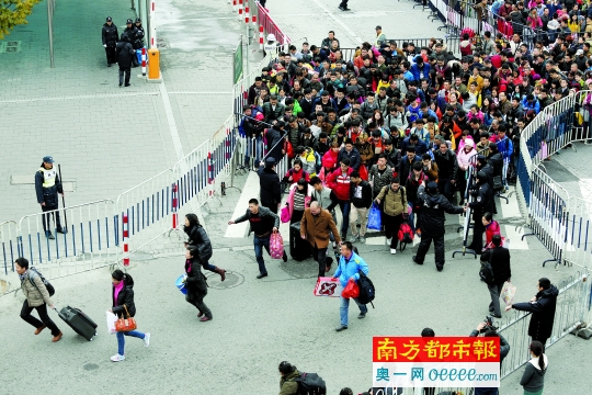 昨日，广州火车站公交站上排队等候进站的旅客冲出限制区域，到前方排队。