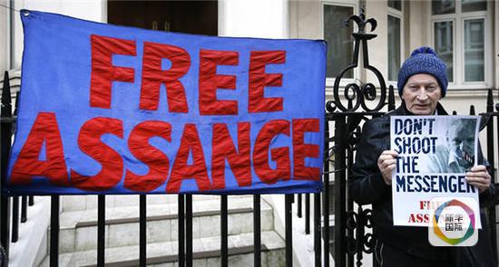 2月4日，在英国首都伦敦，一名支持阿桑奇的男子手持海报在阿桑奇所在的厄瓜多尔使馆外抗议。（图片来源：新华社/美联）
